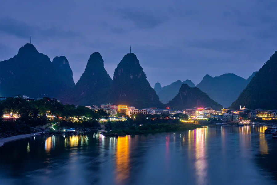 "Vista crepuscular de Yangshuo, con las luces brillantes de la ciudad a la orilla del río
