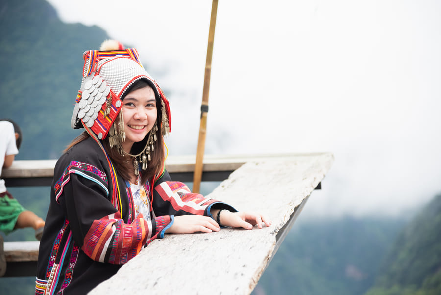 mujer joven sonriente con vestimenta y tocado tradicional de la etnia Akha,